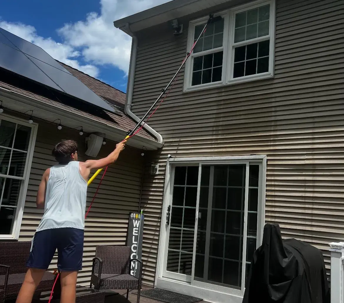 Josh Drumm cleaning a home's exterior with a water-fed pole